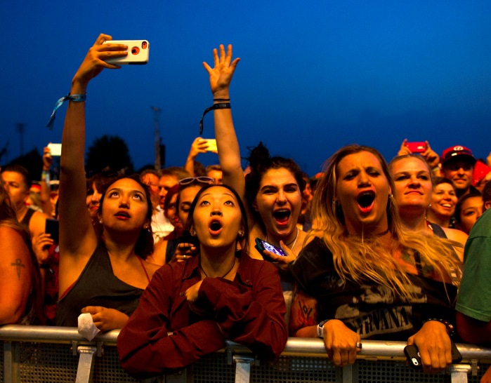 Bella Aguilar takes a selfie, left, as Qury Kim, second from left, Ryleigh Kentera, and Kate Colvin cheer on the Foo Fighters Friday evening at the Whitman College Athletic Fields during the Gentlemen of the Road concert in Walla Walla, Wa. 14 August 2015   (MICHAEL LOPEZ, Union-Bulletin, via AP)