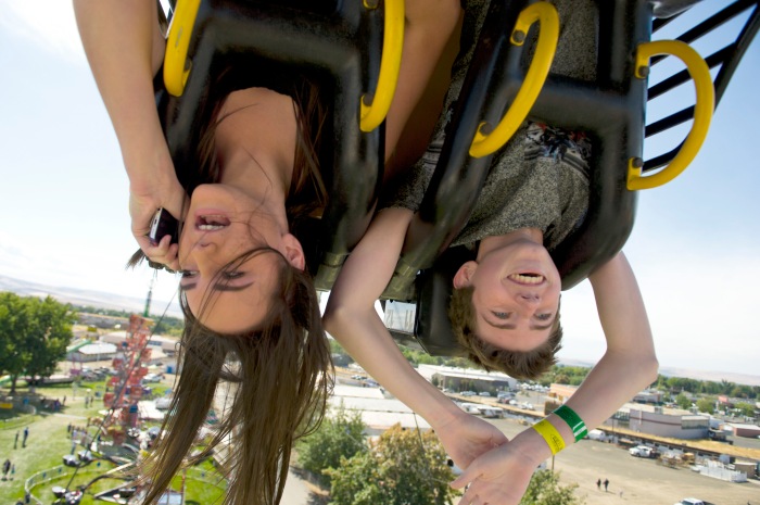 Taylor Lovell, 14, talks to her mom on the phone as she and her friend Mathew Nickleson hang upside down on the Fireball ride during the Walla Walla Fair & Frontier Days Friday morning in Walla Walla, Wa. 04 September 2015     (MICHAEL LOPEZ/Walla Walla Union-Bulletin via AP)
